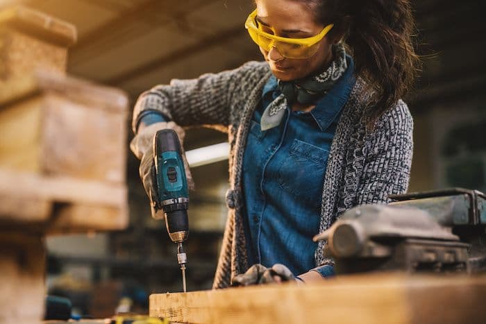 Mujer utilizando un taladro en un proyecto de ensamblaje de madera.