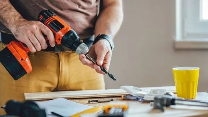 Manos de carpintero utilizando un taladro para asegurar las uniones de madera.