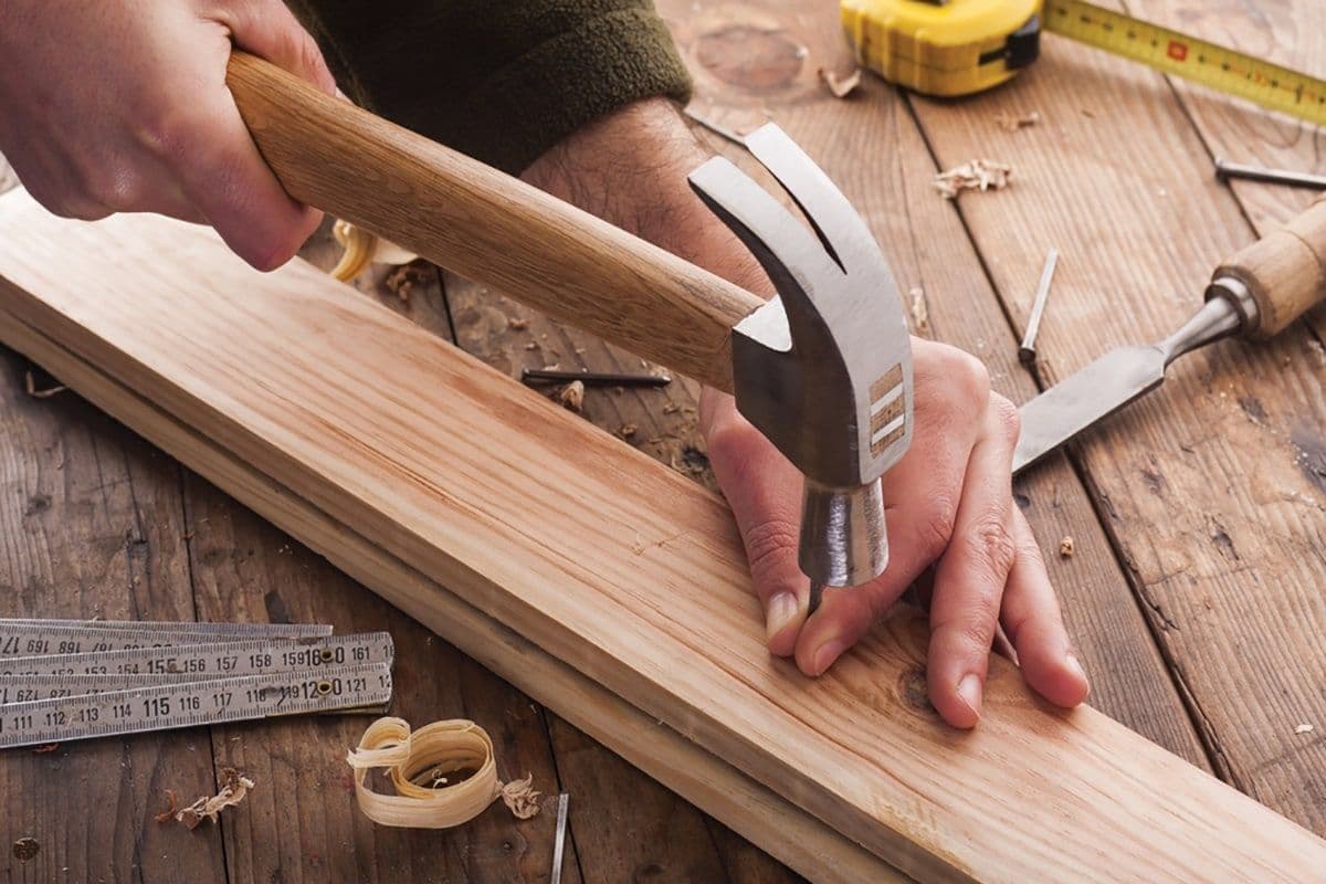 Manos de carpintero utilizando herramientas de sujeción para asegurar uniones de madera.