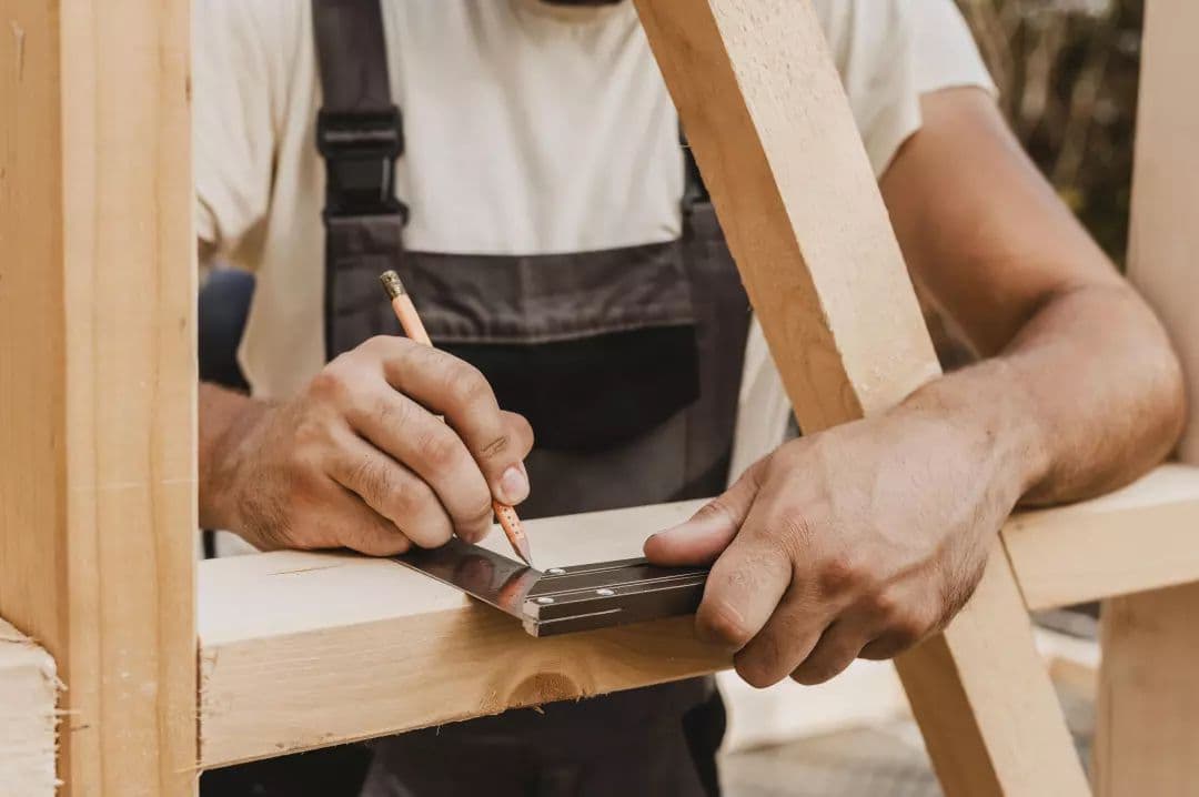 Detalle de las manos de un carpintero midiendo con cinta métrica, destacando el uso de productos de alta calidad.