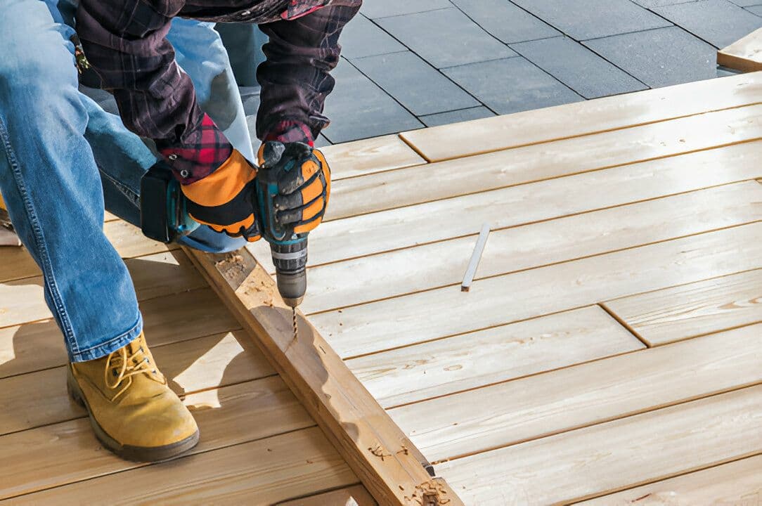 Carpintero utilizando un taladro en una construcción de madera, representando la variedad de herramientas ofrecidas por Ferretería Guevara.