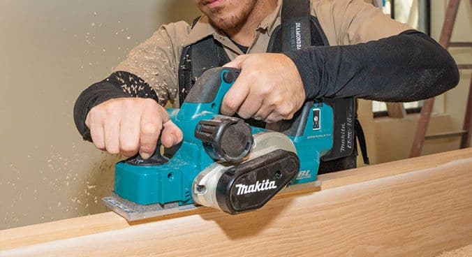 Carpintero utilizando una cepilladora Makita para trabajos de precisión en madera.