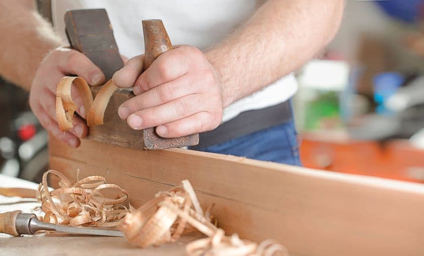 Carpintero utilizando un formón para trabajar detalles en madera.